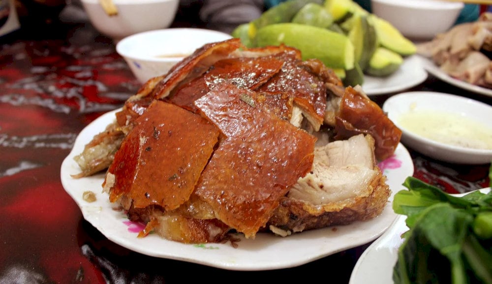 Slices of crispy pork skin and moist meat, served with chili salt and local herbs